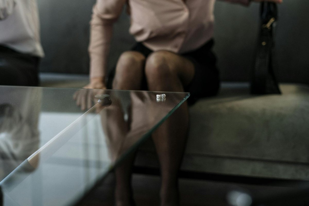 A wedding ring on a glass table symbolizes divorce and relationship issues.