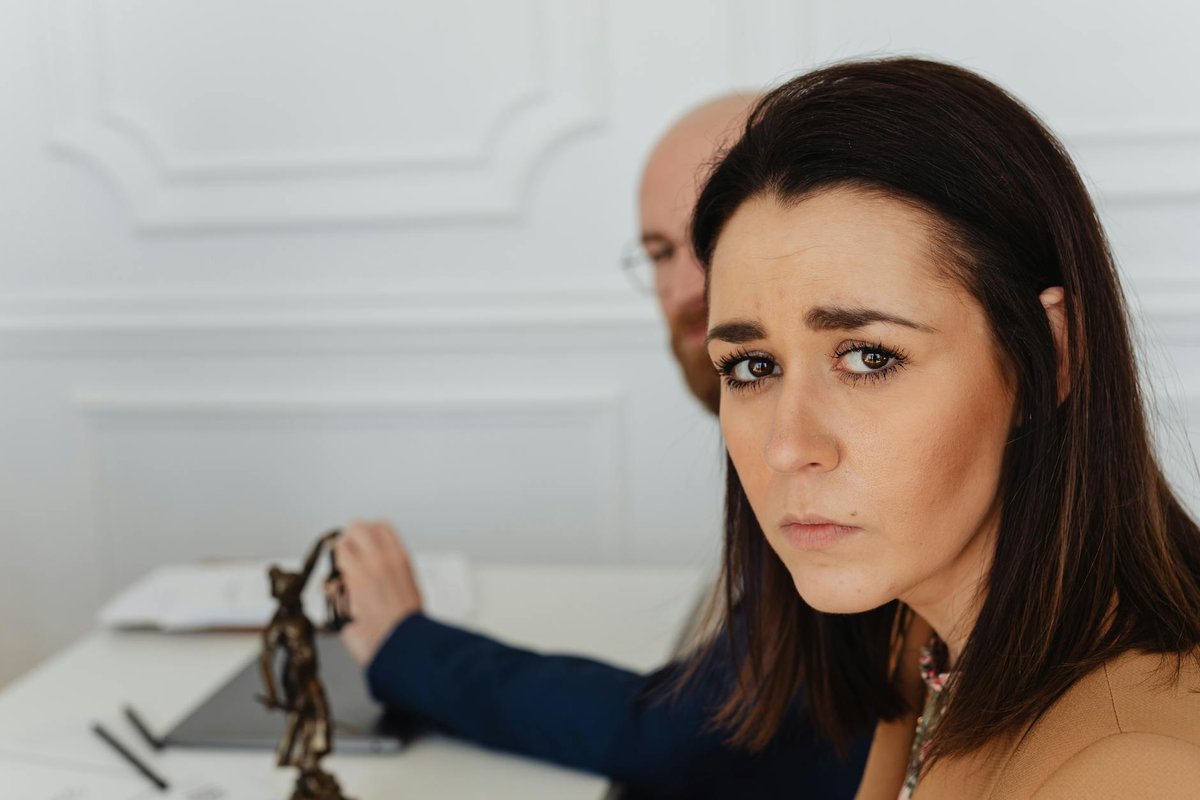 Close-up of a worried Caucasian woman sitting in an office environment, looking at the camera.