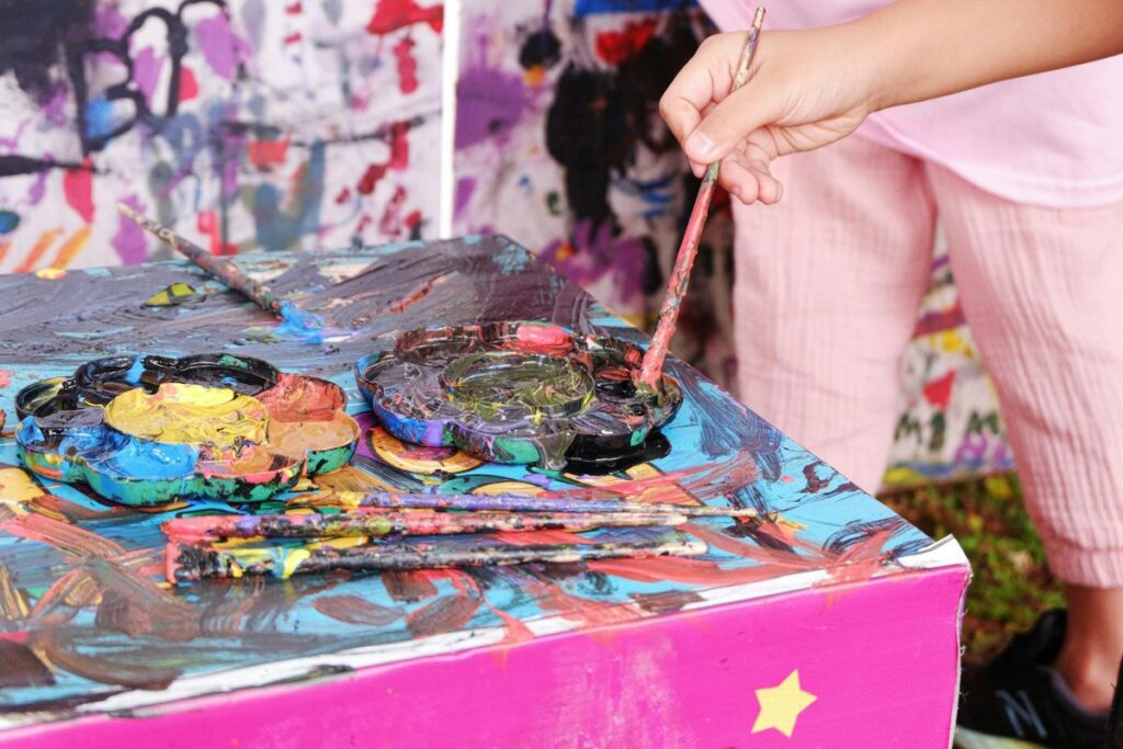 A young girl creatively painting using a vibrant palette in Jakarta, Indonesia.