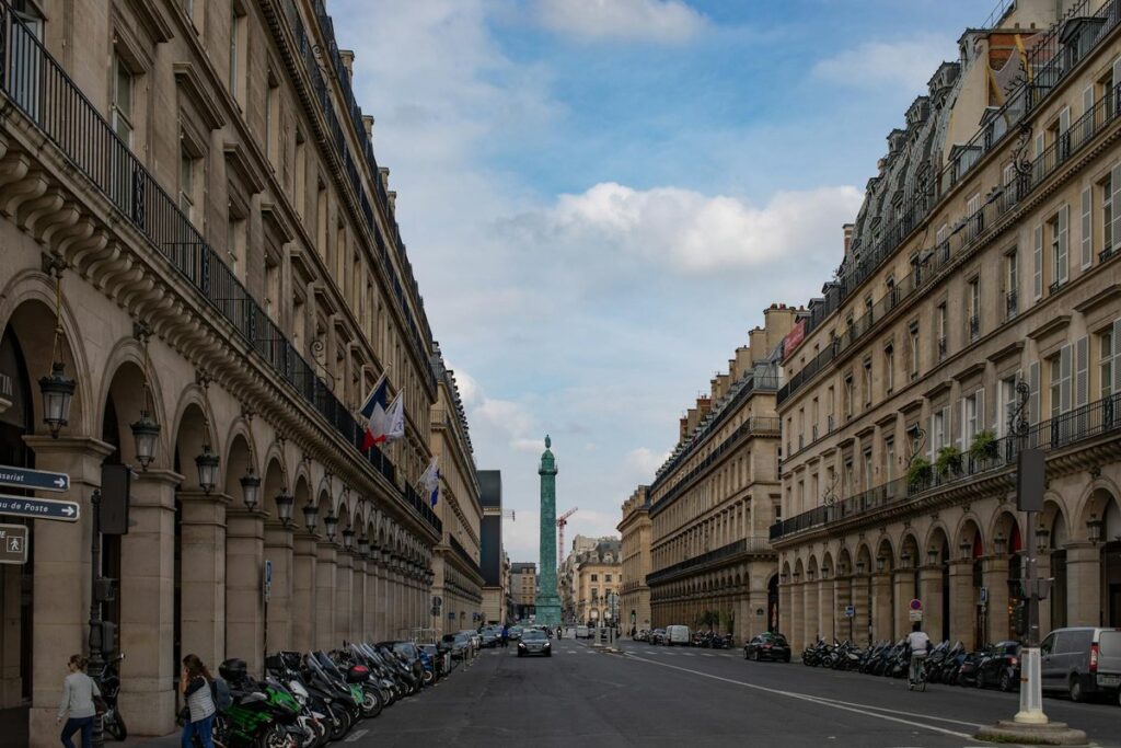 View of the historic Colonne Vendôme in Paris with classic architecture and street life.