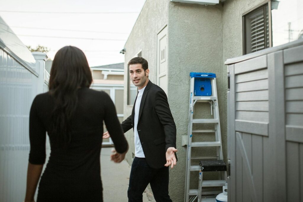 A couple having a tense conversation outside near a ladder.