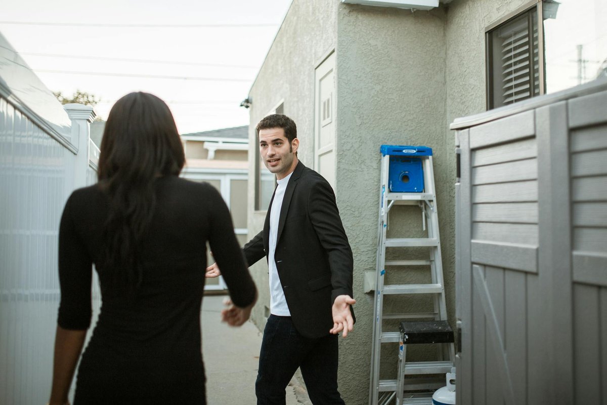 A couple having a tense conversation outside near a ladder.