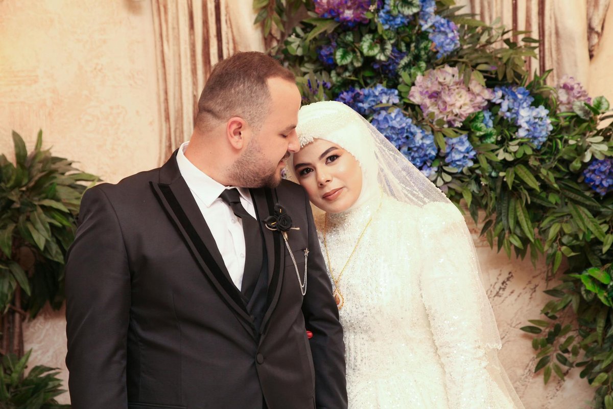 Elegant wedding couple portrait with floral background, indoors.