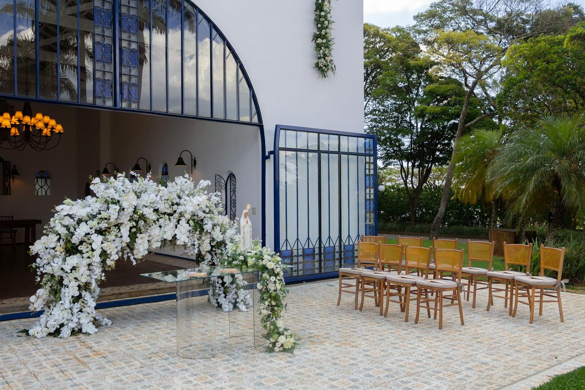 Beautiful outdoor wedding setup with floral arch and wooden chairs in São Paulo, Brazil.