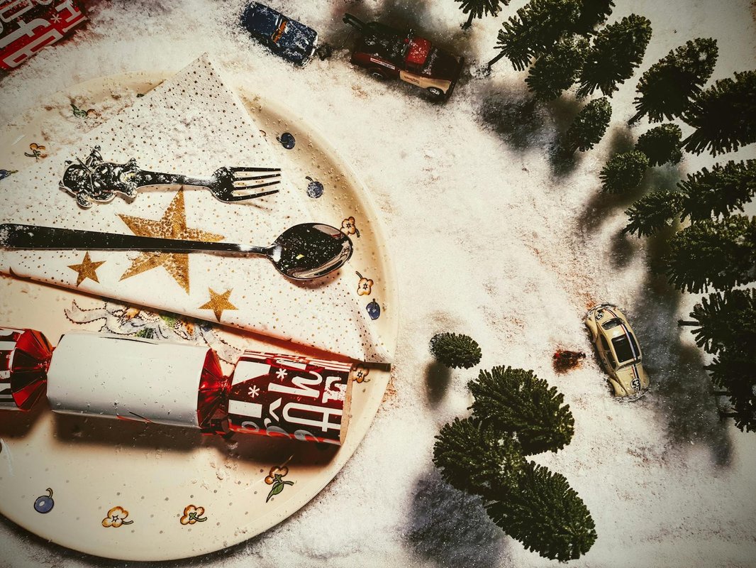 Playful Christmas scene with miniature cars and trees set in artificial snow, conveying a festive winter atmosphere.