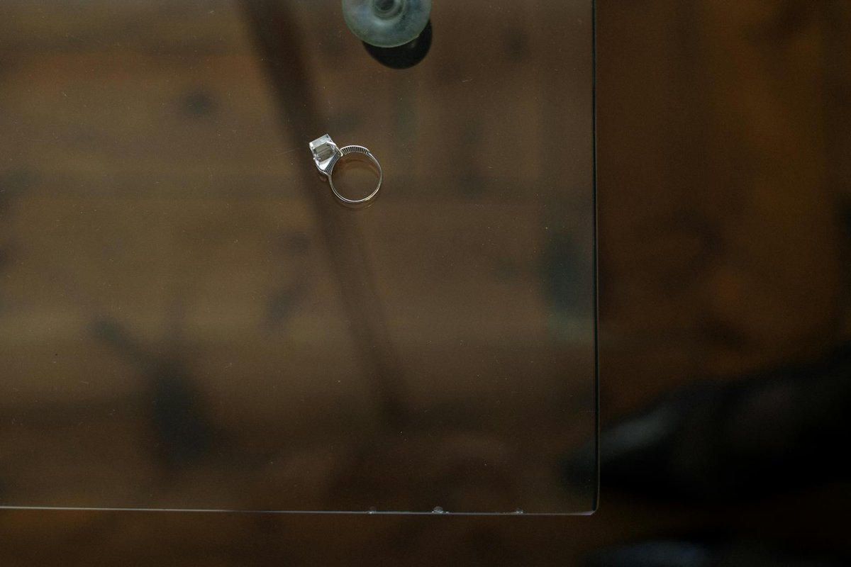 A single engagement ring rests on a glass table, symbolizing relationship reflection.