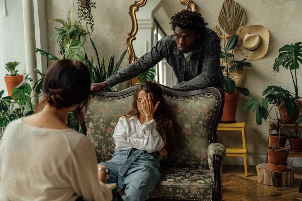 A supportive counselor interacting with a couple during an emotional therapy session in a cozy setting.