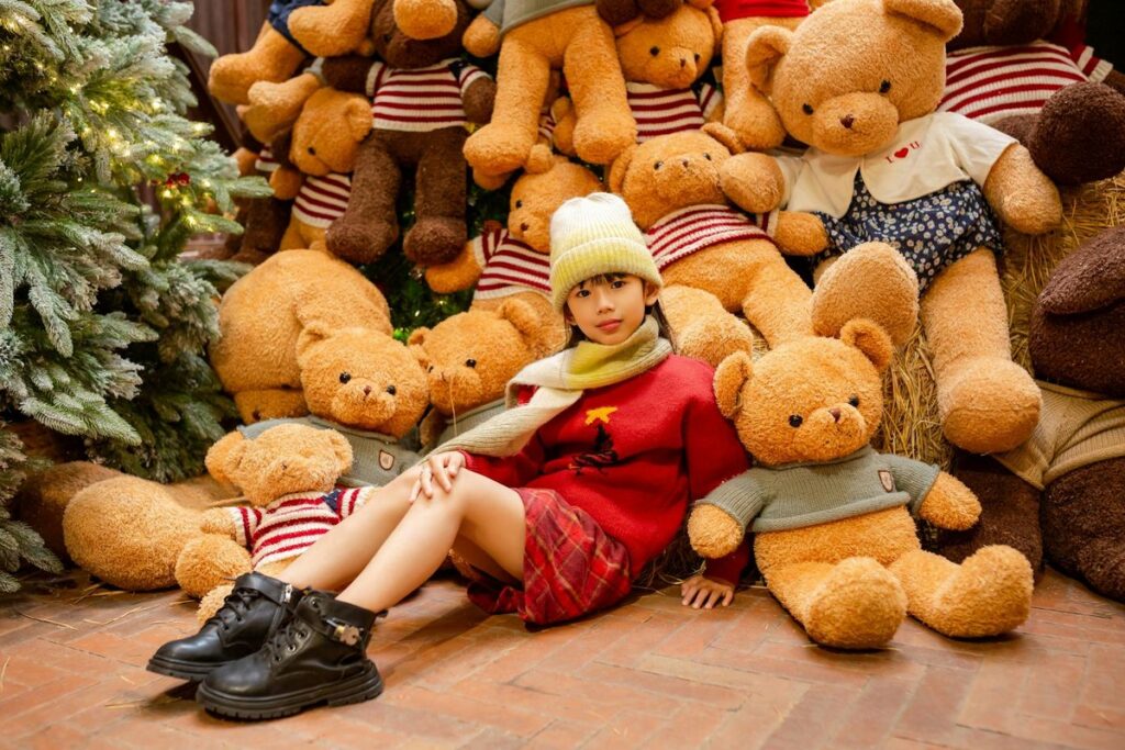 A child sitting among teddy bears in a festive indoor setting, exuding warmth and coziness.