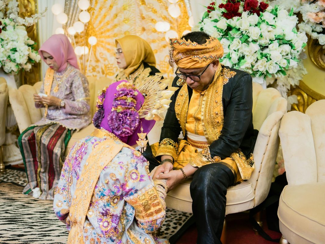 A vibrant traditional wedding ceremony taking place indoors in Kendari, Indonesia.