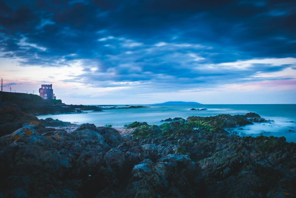 Dramatic coastal view with lighthouse at dusk in Dublin, Ireland. Perfect for travel and nature enthusiasts.