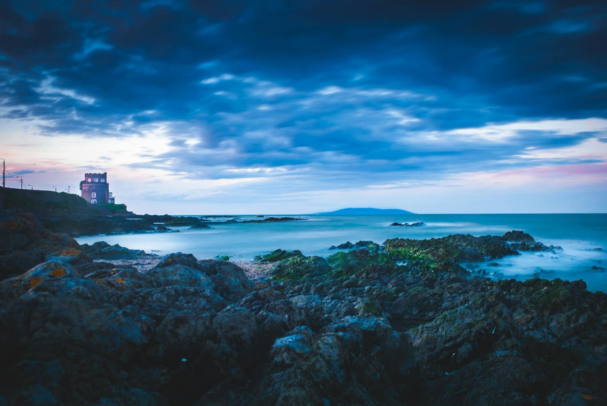 Dramatic coastal view with lighthouse at dusk in Dublin, Ireland. Perfect for travel and nature enthusiasts.