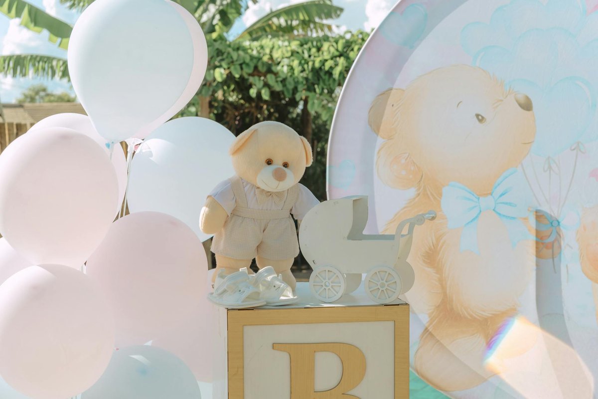 Adorable baby shower decoration featuring balloons, a stuffed teddy bear, and stroller cutout, creating a joyful atmosphere.