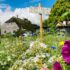 Colorful flower meadow in front of a cozy Danish cottage under a vibrant summer sky.