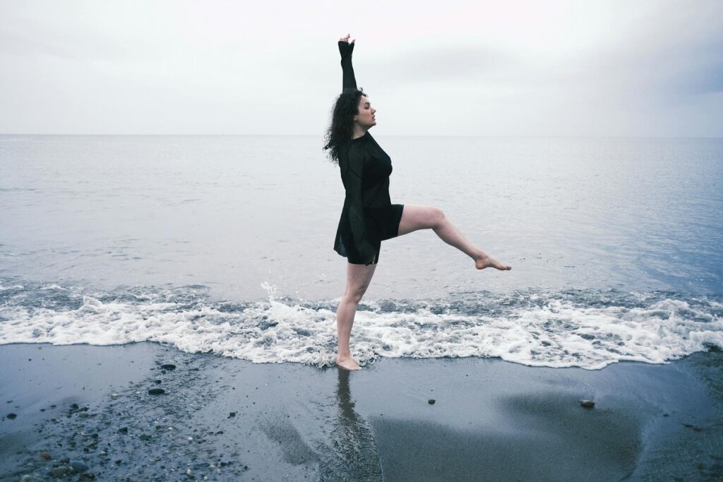 A woman enjoying a serene moment stretching by the ocean in Killiney, Ireland.