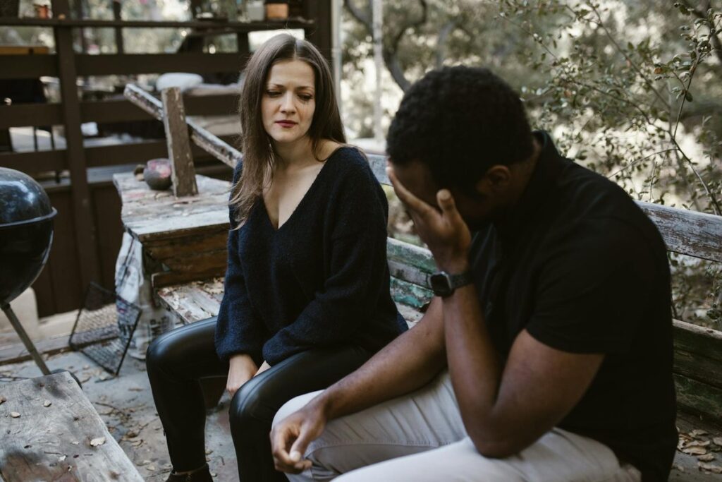 A couple having an emotional conversation outdoors, conveying sadness and concern.