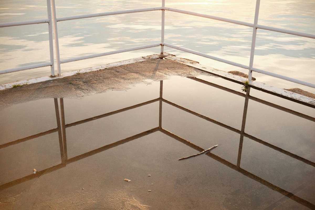 Peaceful lakeside scene with reflections on a pier during sunset.