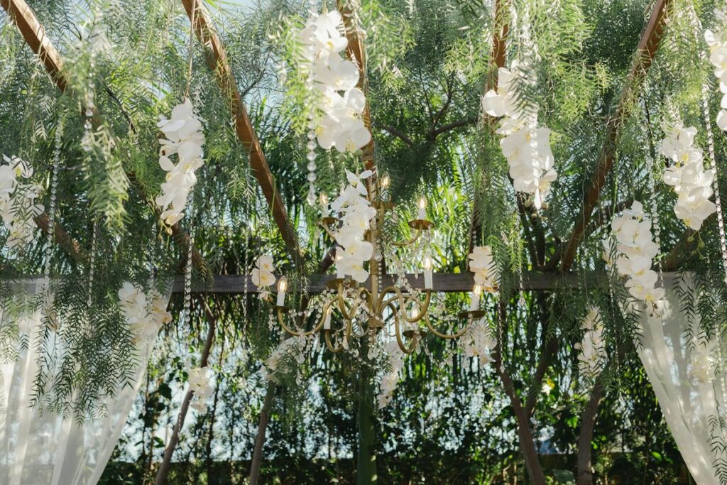 Elegant wedding decor featuring a chandelier adorned with white orchids and greenery.