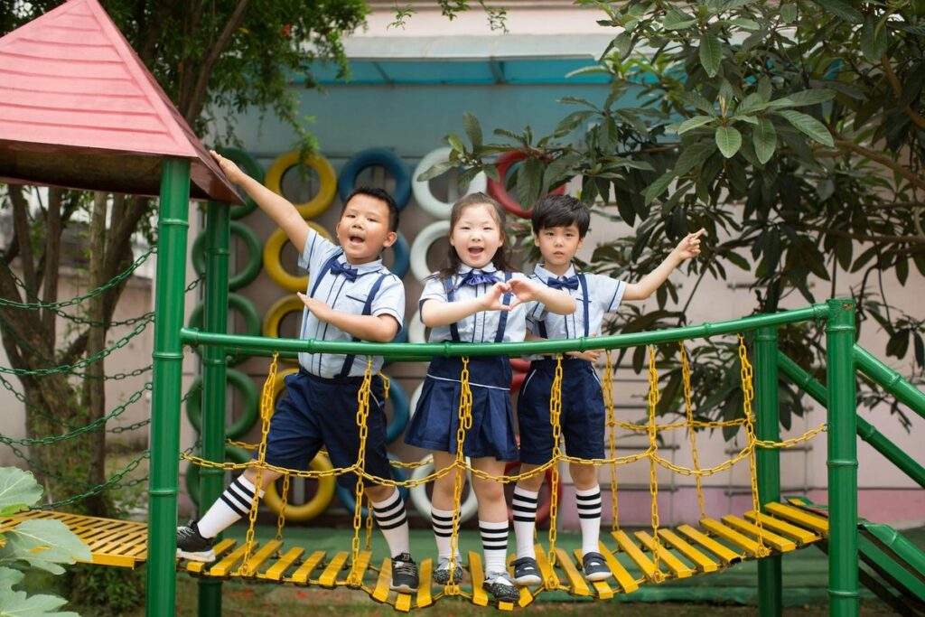 Three children enjoying a playful day on a colorful playground bridge outdoors.