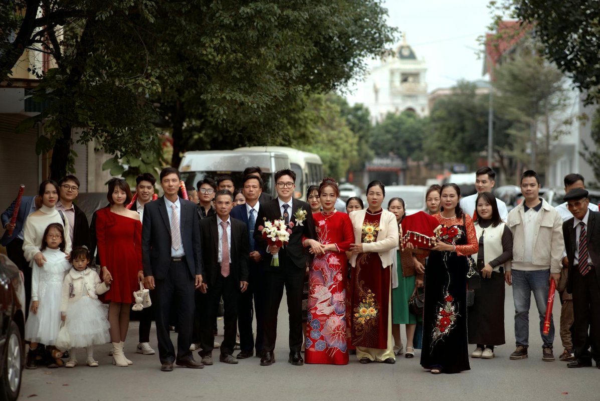 A large group of people in traditional attire celebrating a wedding outdoors.