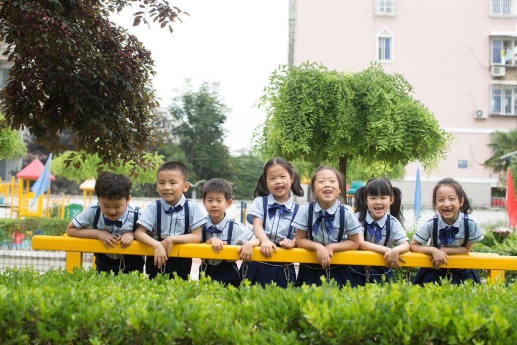 A group of cheerful students in school uniforms enjoying time outdoors at a playground.
