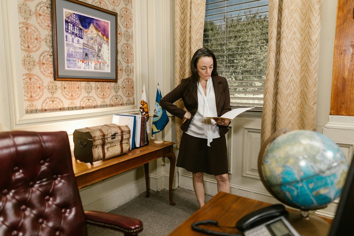A woman in a professional office setting reviewing documents with focus and intent.