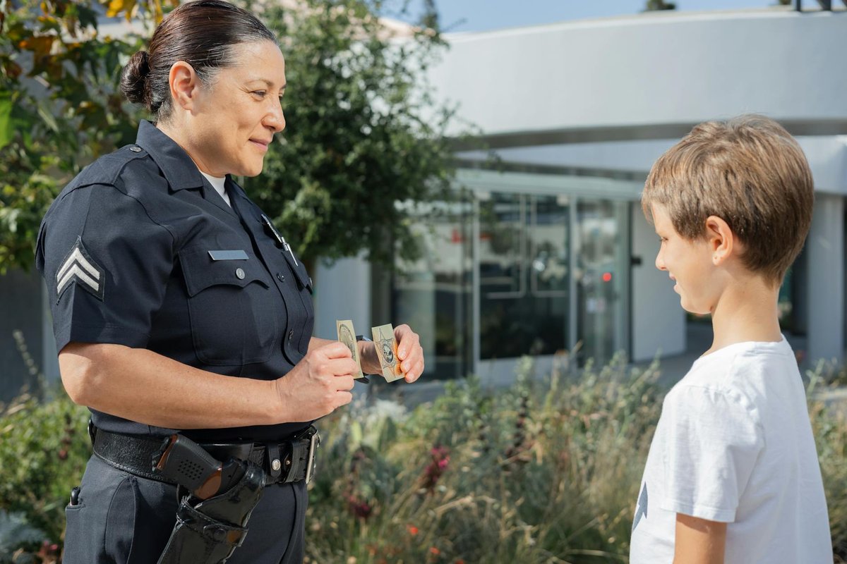 A policewoman showing her badge to a young boy in an outdoor setting.