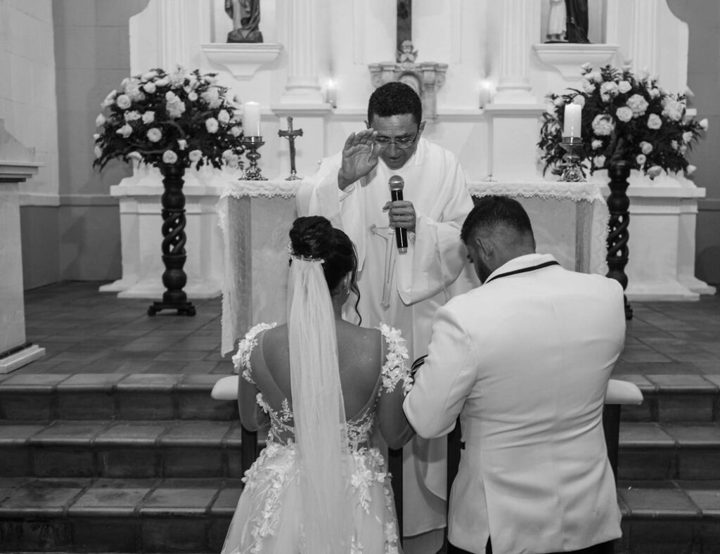 A couple receives a blessing from a priest during their church wedding ceremony.