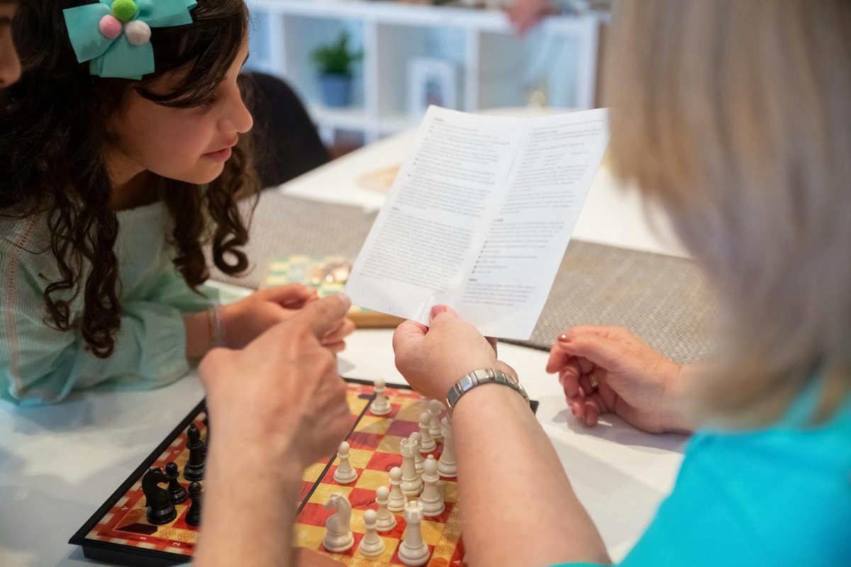 Close-up of a police officer handcuffing an individual against a metal fence outdoors.