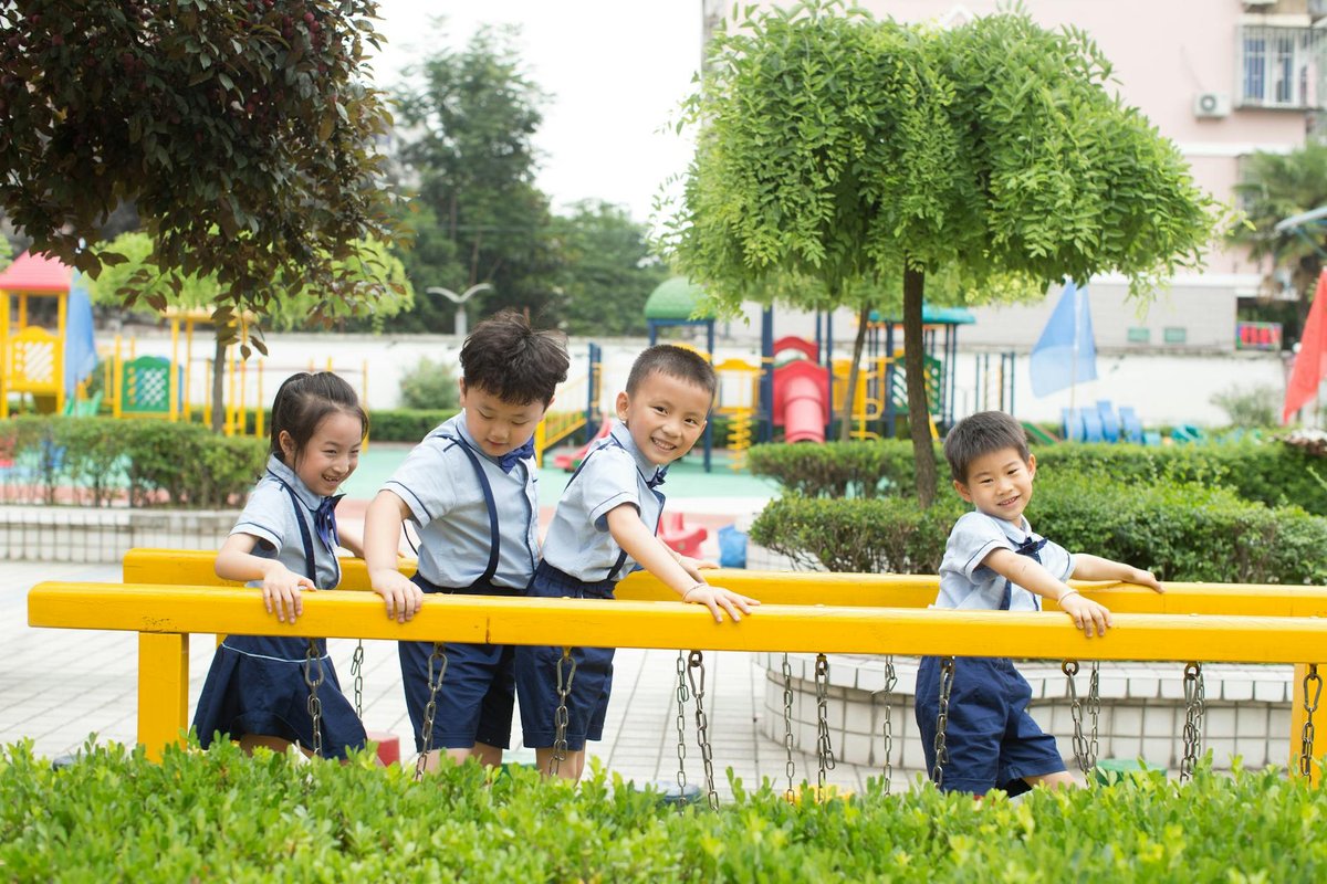 Group of children in uniforms playing on a playground slide, enjoying outdoor fun.