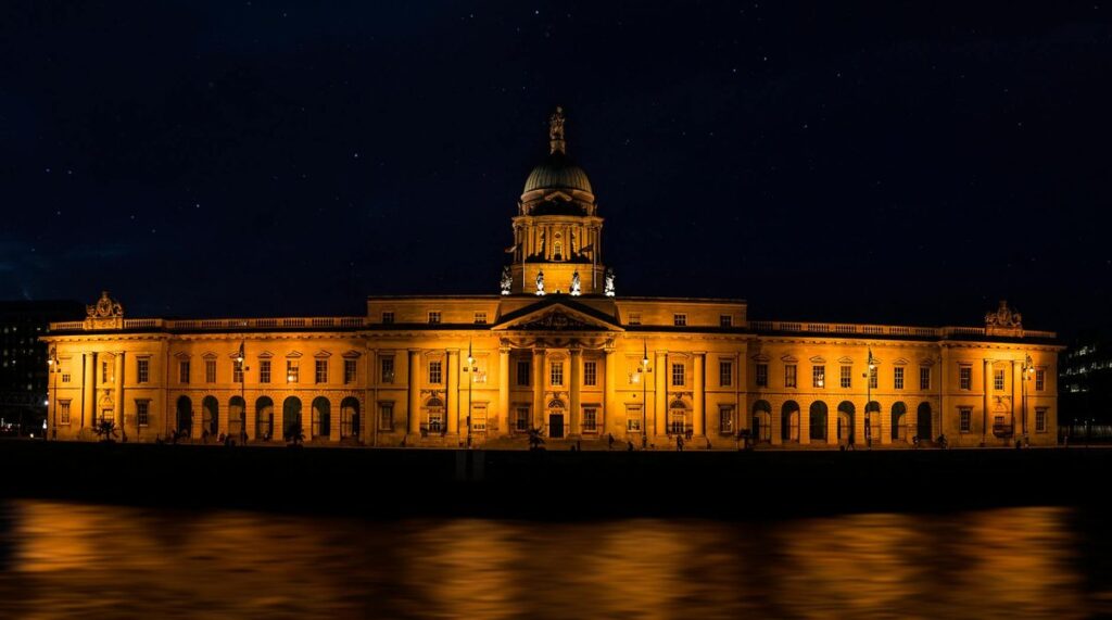 Stunning view of the illuminated Custom House in Dublin by the river at night.