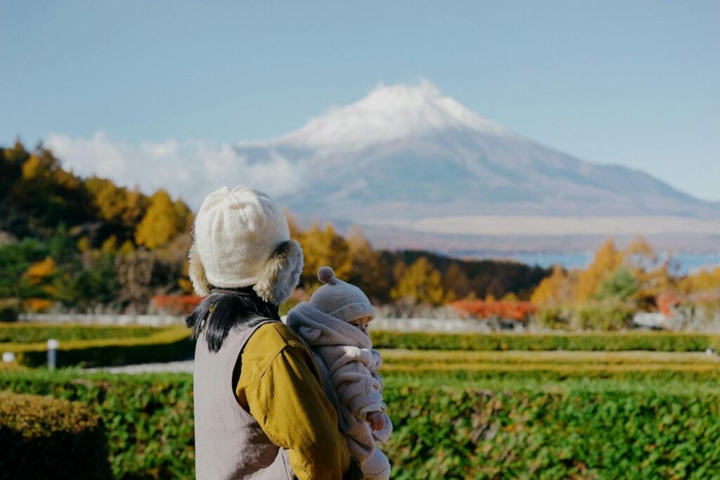 A mother and her baby enjoy a scenic autumn view of Mount Fuji in Fujinomiya, Japan.