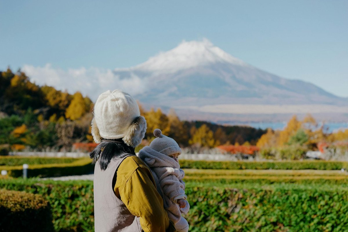 A mother and her baby enjoy a scenic autumn view of Mount Fuji in Fujinomiya, Japan.