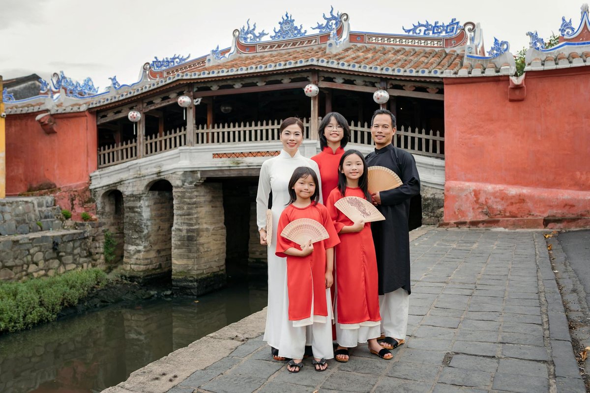 A Vietnamese family in traditional attire poses by the iconic Japanese Bridge in Hội An.