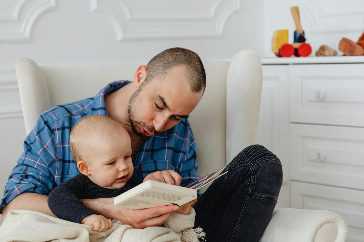 A police officer stands by two prisoners in jail uniforms behind bars, indoors.