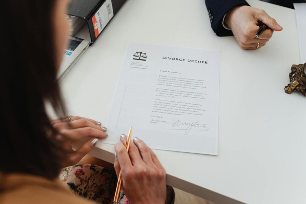 A close-up shot of two people signing a divorce decree at a law office table.