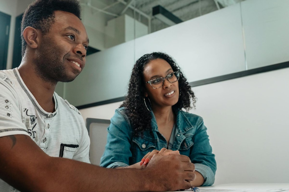 A happy couple in an office setting conversing and smiling during a meeting with a consultant.