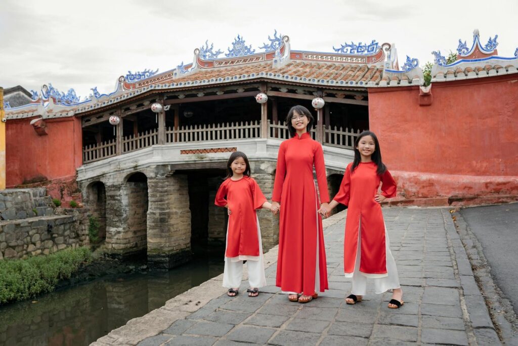A family in red ao dai poses at the historic Japanese Bridge in Hoi An, Vietnam.