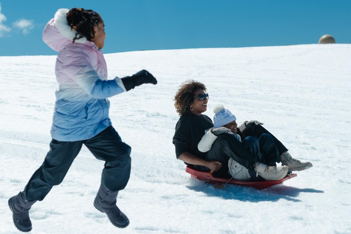 Happy family enjoying sledding on a sunny winter day, capturing fun and joy.