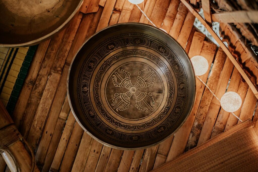 A traditional singing bowl resting on a bamboo surface with warm ambient lighting.