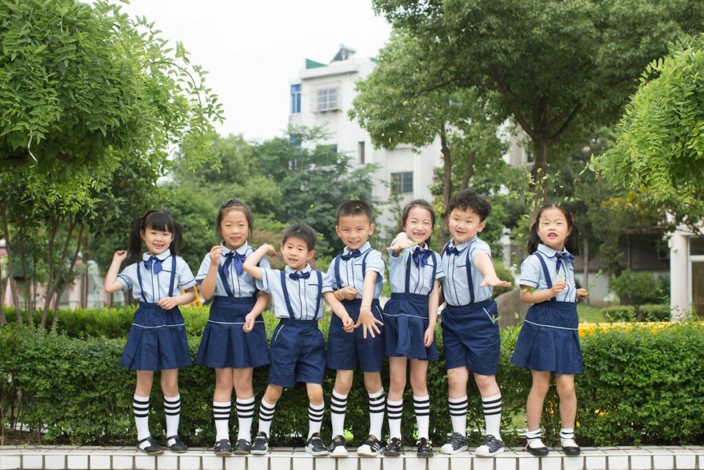 Joyful group of children in school uniforms posing outdoors, symbolizing friendship and education.