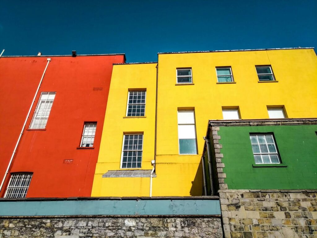 Vibrant red, yellow, and green buildings in Dublin under a clear blue sky.