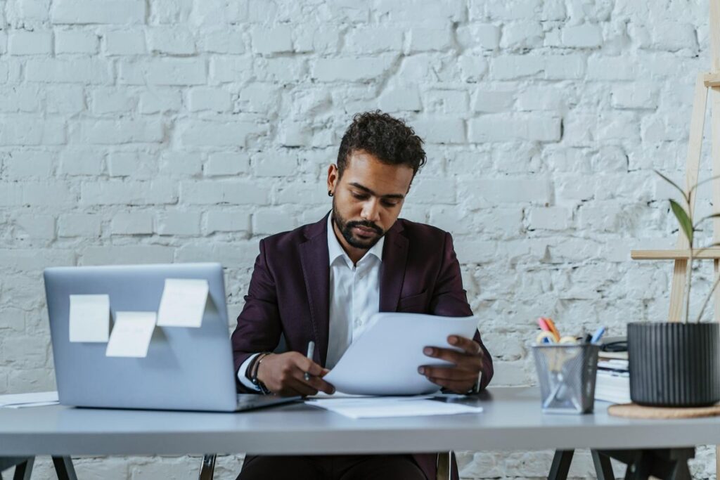 A professional man reviews documents in a modern office setting, focused on his work.