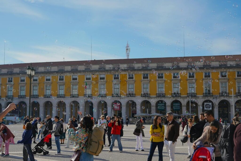 A lively day at Praça do Comércio in Lisbon, filled with people and bubbles.