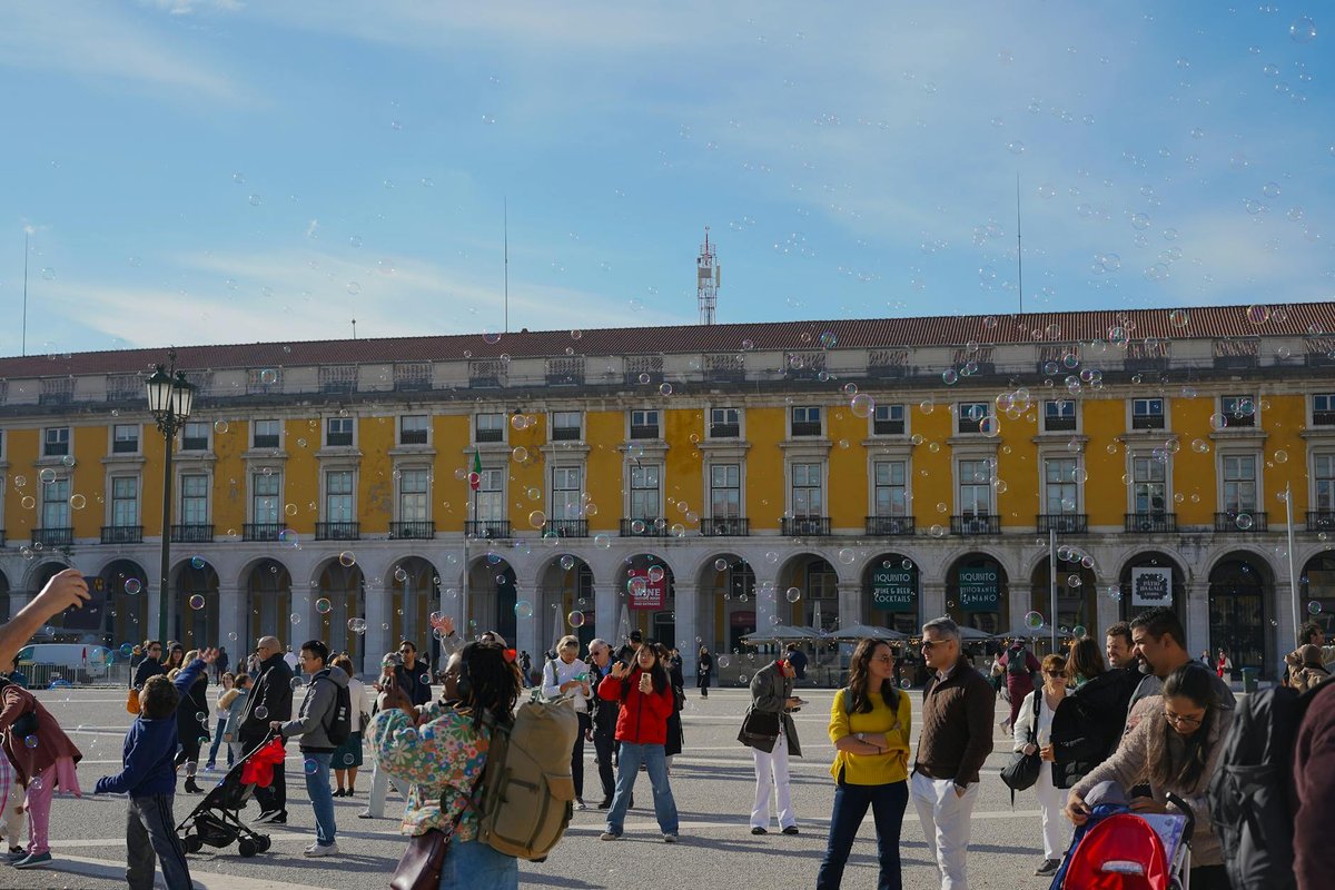 A lively day at Praça do Comércio in Lisbon, filled with people and bubbles.