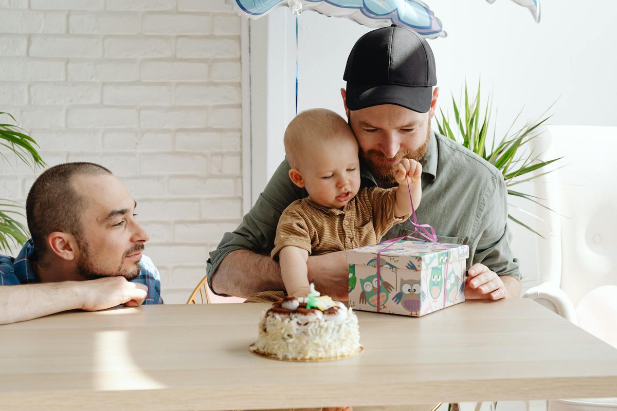 A family celebrates their toddler's birthday with gifts and cake, capturing a heartwarming moment.