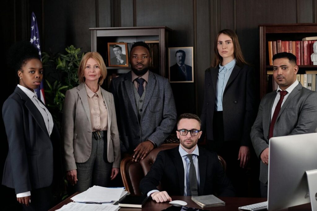 A diverse group of business professionals posing in an office, showcasing teamwork and leadership.