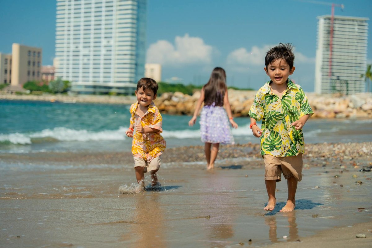 Three children enjoying a playful day at the beach with waves, sand, and sunshine.