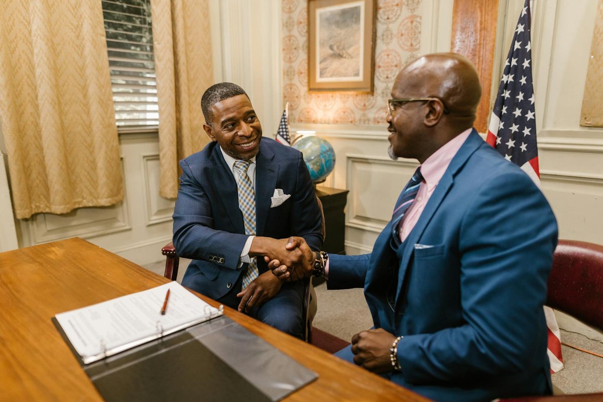 Two professionals in a law office shake hands, showcasing a positive business agreement.