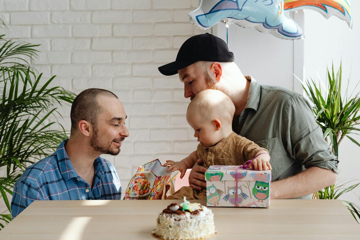 A joyful family celebrating with their baby, surrounded by gifts indoors.