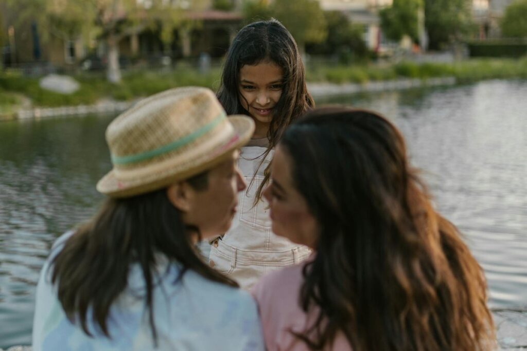 A joyful family moment by the lakeside featuring two women and a smiling child.